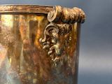 a silver vase with a lion head on the handle