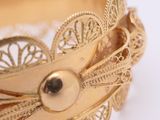 a close up of a gold bracelet on a white surface