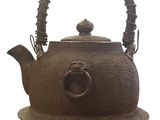 a brown tea pot with a handle on a plate