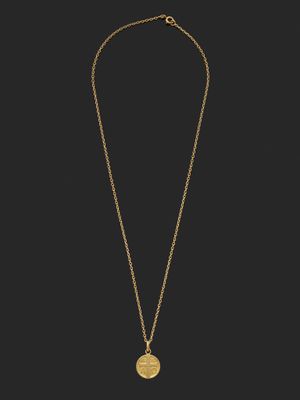 un collier en or orné d'une pièce de monnaie sur fond noir