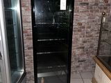 a black refrigerator in a room with a brick wall behind it