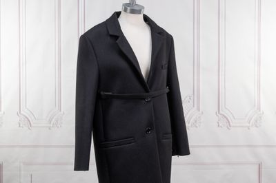 une image d'un manteau noir sur un support de mannequin