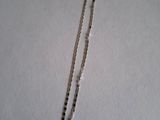 a close up of a silver chain with black beads on a white surface