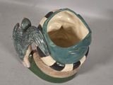 a green and black vase with a bird on it