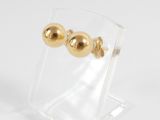 a close up of a pair of gold earrings on a clear stand
