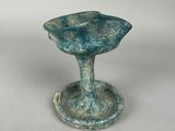 a close up of a small blue vase on a white surface