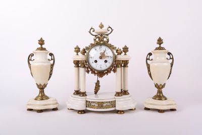trois vases blancs et dorés et une horloge posés sur une table
