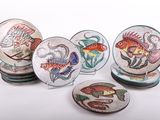 six assiettes ornées de motifs de poissons, posées sur une surface blanche