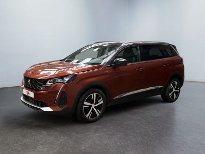 Une voiture rouge est garée dans une pièce aux murs blancs