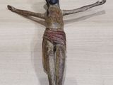 une petite statue représentant une personne sur une croix, posée sur une table