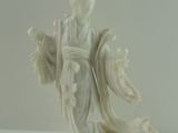 une statue représentant une femme vêtue d'une robe blanche, posée sur une table blanche