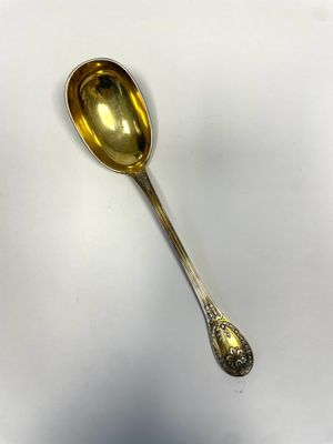 a silver spoon with a gold spoon handle on a white surface