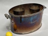 a metal container with three cups in it and a lemon on the table