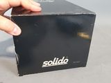 a hand that is holding a black box with the word solido on it