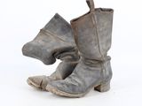 une vieille paire de bottes dont le talon est cassé, sur fond blanc