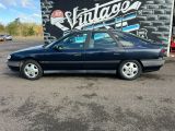 an image of a blue car parked in front of a vintage sign