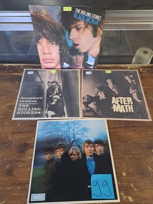 the rolling stones album covers are sitting on a table in front of a glass case