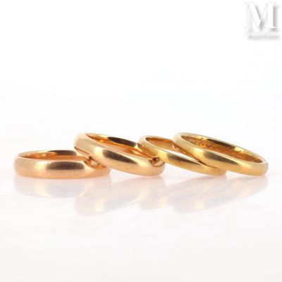 three gold wedding rings sitting on top of a white surface
