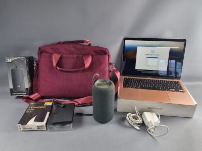 un ordinateur portable et d'autres objets posés sur une table, à côté d'un sac