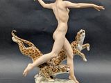 figurine of a nude woman with leopards on a black background