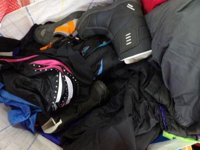 a pile of clothes and a pair of shoes on a bed
