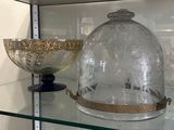 a glass display case with a bowl and a glass clochet on it