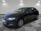Une Audi noire est garée dans une grande pièce au sol carrelé.