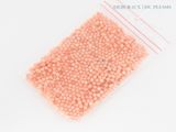 a close up of a bag of pink beads on a white surface
