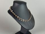 a black mannequin with a gold chain and a black hat on a stand