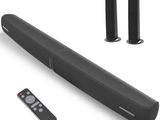 deux enceintes noires et une télécommande posées sur une surface blanche