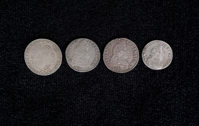 four different types of silver coins on a black surface