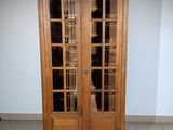 a tall wooden cabinet with glass doors in a room