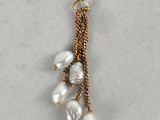 a close up of a pair of earrings with pearls hanging from them