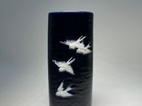 a black vase with white birds on it on a white surface
