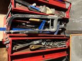 de nombreux outils posés sur une étagère rouge dans un garage