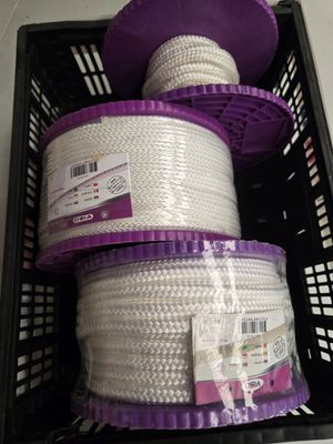 plusieurs rouleaux de corde blanche dans un panier en plastique posé sur une table