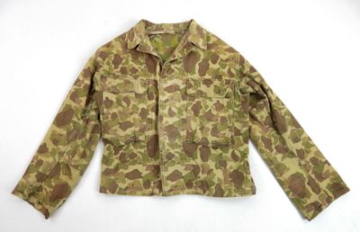 La veste est confectionnée dans un tissu camouflage et possède des manches longues.