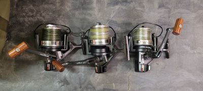 three fishing reels are lined up on a wall next to each other