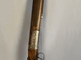 un vieux pistolet avec une poignée en bois sur une surface blanche