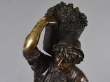 bronze statue of a man with a basket of grapes on his head