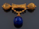 une image représentant une broche en or et en lapis-lazuli sur un fond noir