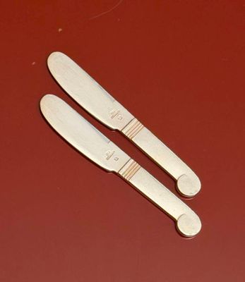 two knives that are sitting on a red surface
