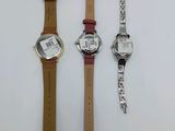 three different watches sitting on top of a white surface next to each other