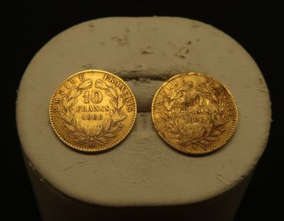two gold coins sitting on top of a white pedestal