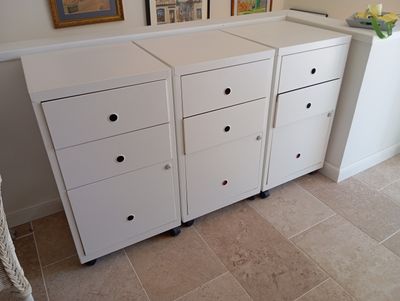 une photo d'un meuble blanc à tiroirs et de tableaux accrochés au mur
