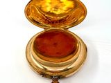 a gold case with a red stone inside of it