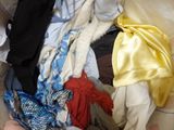 a pile of clothes sitting on a bed with a person standing next to it