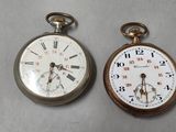 two old pocket watches sitting next to each other on a table