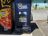 une boîte à pizza ornée d'une couronne, à côté d'une poubelle
