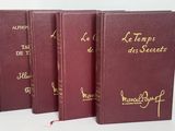 trois livres rouges ornés d'inscriptions dorées, posés sur une table